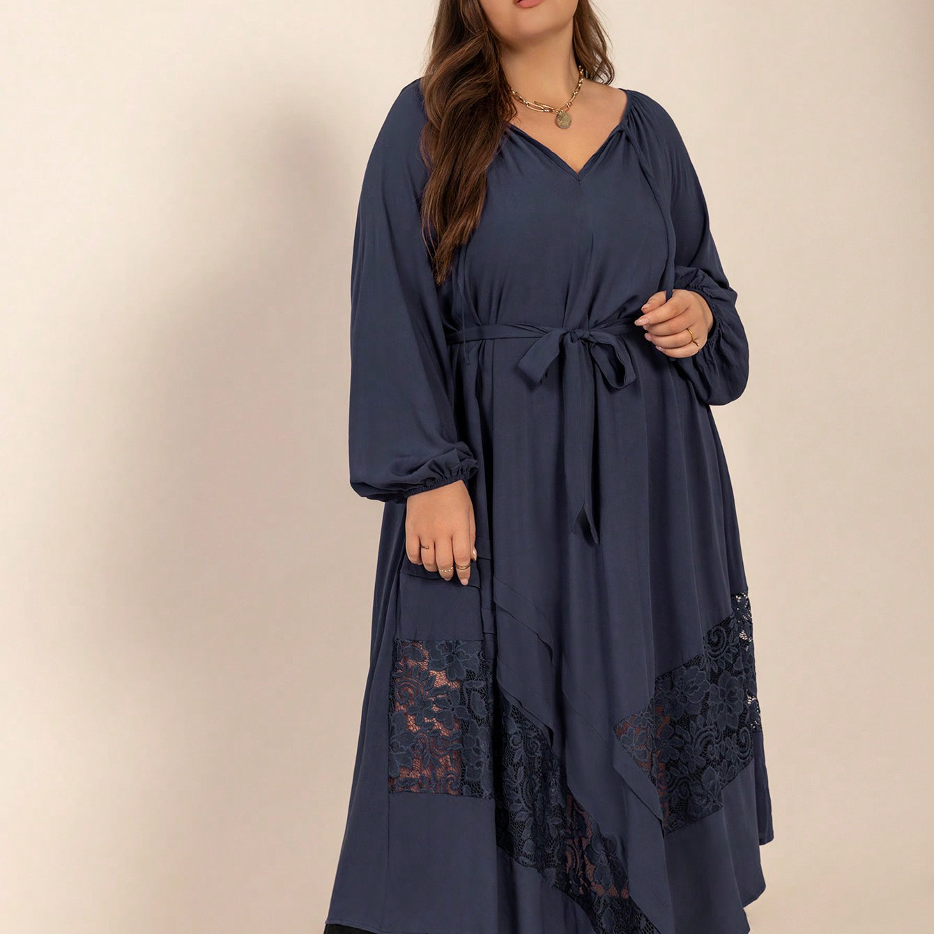 Woman wearing a dark blue winter cozy dress with lace details and waist tie