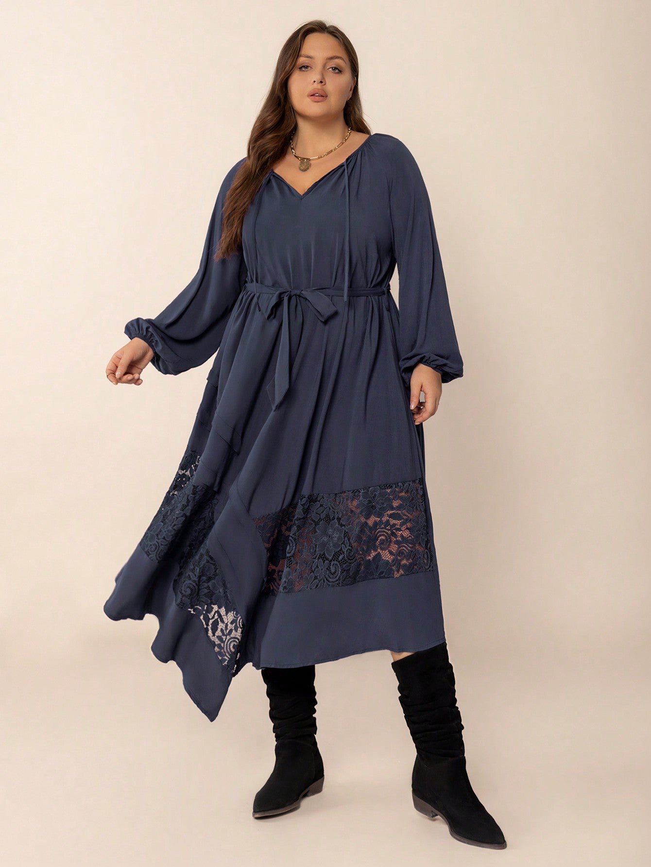 Plus-size woman wearing a dark blue winter cozy dress with lace panels and tie waist