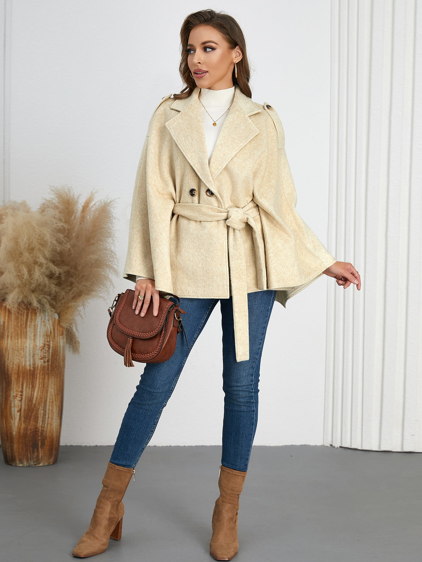 Woman in a belted beige cape coat, showcasing stylish ملابس for winter fashion
