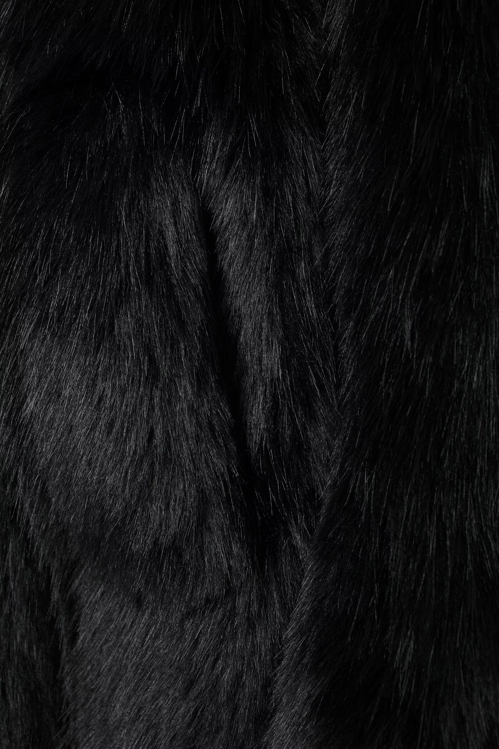 Black faux fur fabric with a luxurious shaggy texture for fashionable warmth