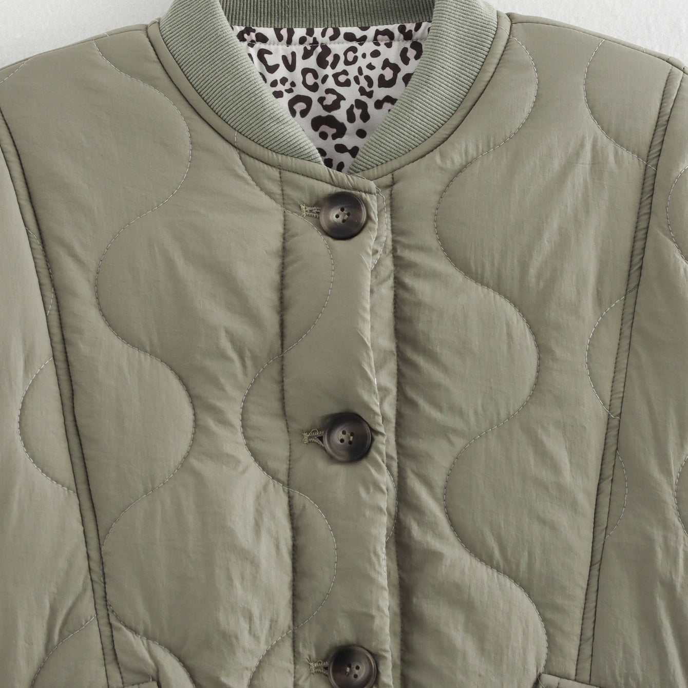 Quilted olive jacket with animal print lining, a stylish addition to any fashion wardrobe