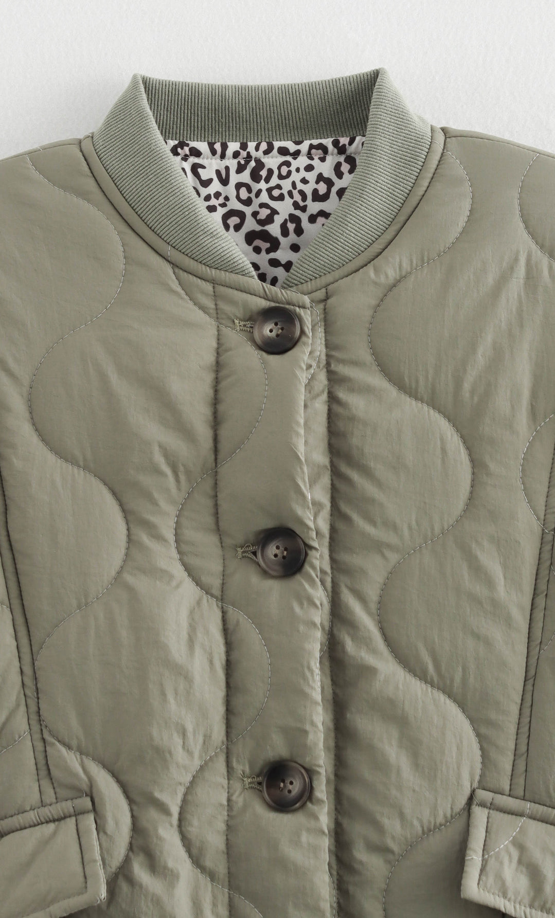 Quilted olive jacket with animal print lining, a stylish addition to any fashion wardrobe