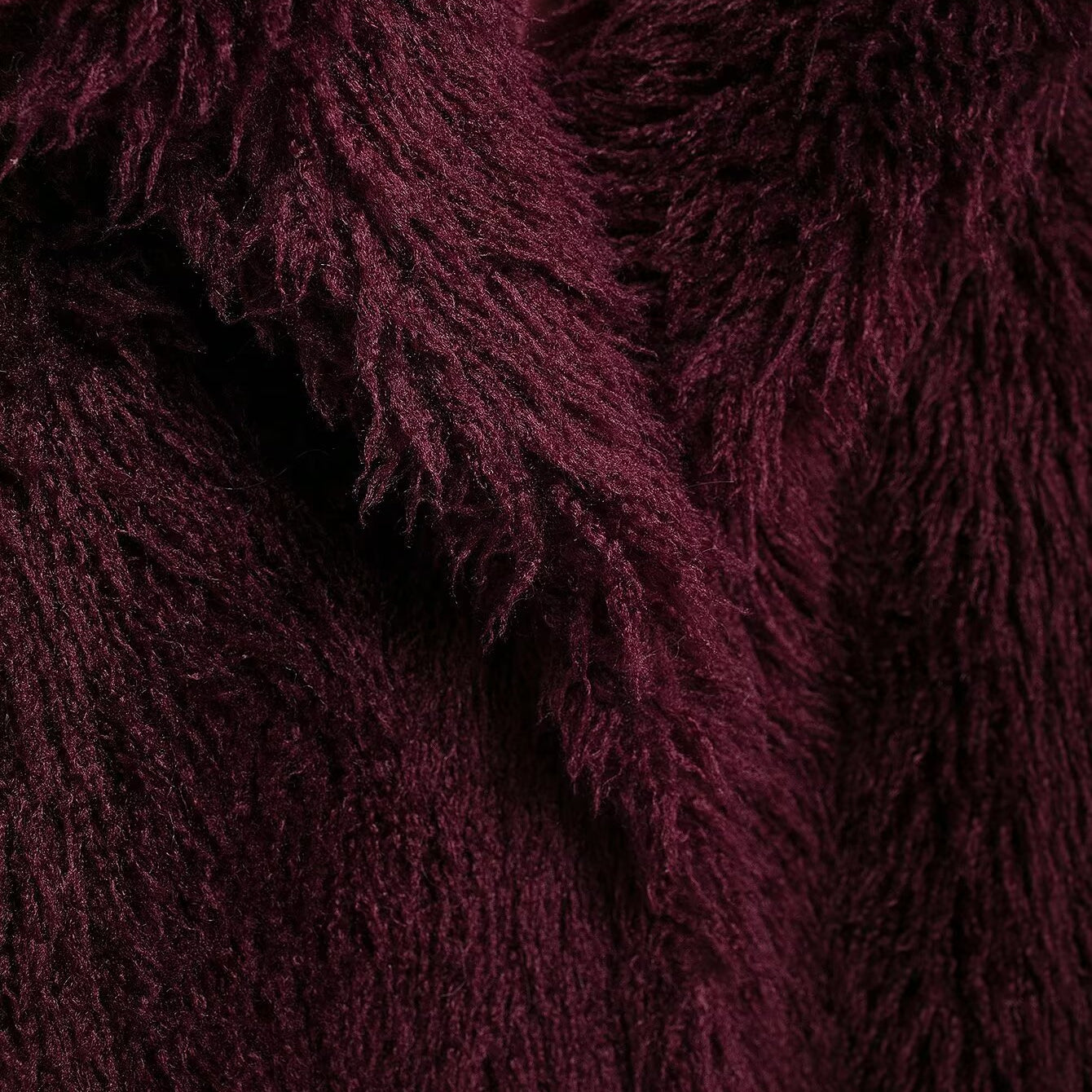 Close-up of a burgundy faux fur garment with shaggy texture from the Faux Fur Effect Mid Length Coat collection