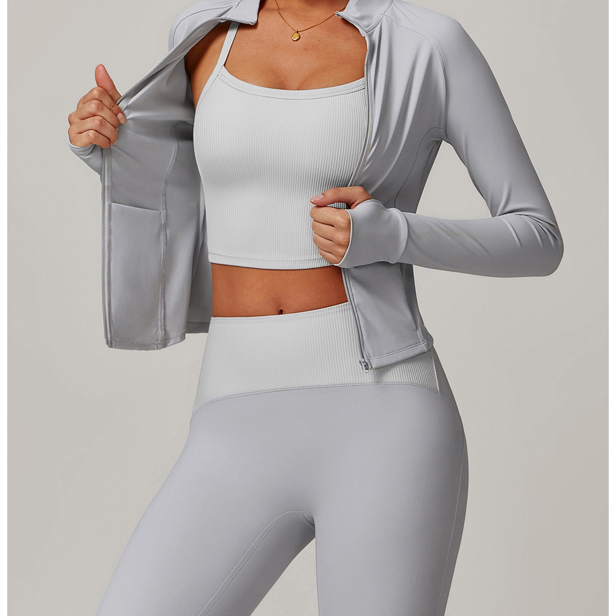 Light gray athletic workout set featuring a zip-up jacket, crop top, and leggings for yoga fashion