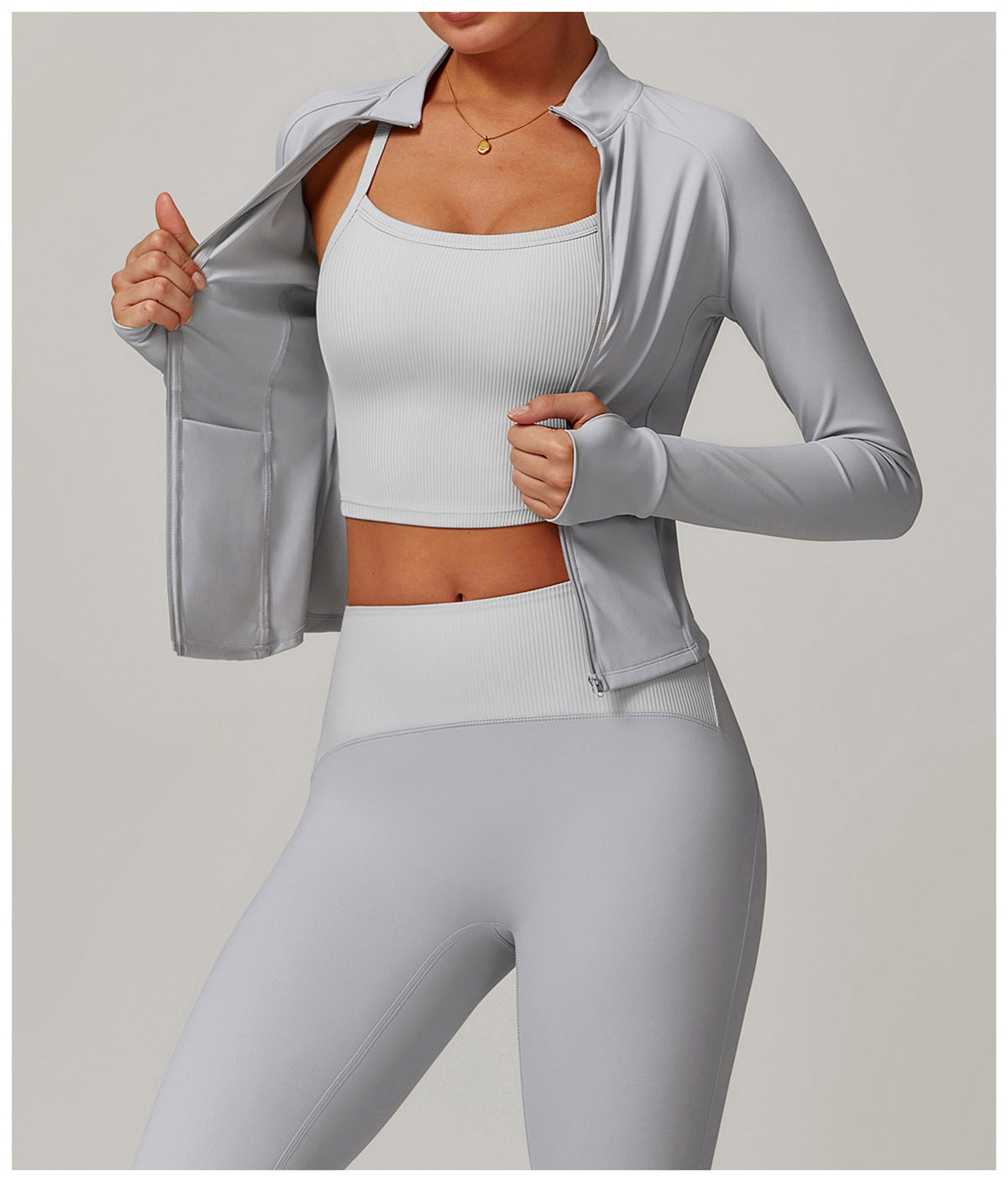 Light gray athletic workout set featuring a zip-up jacket, crop top, and leggings for yoga fashion