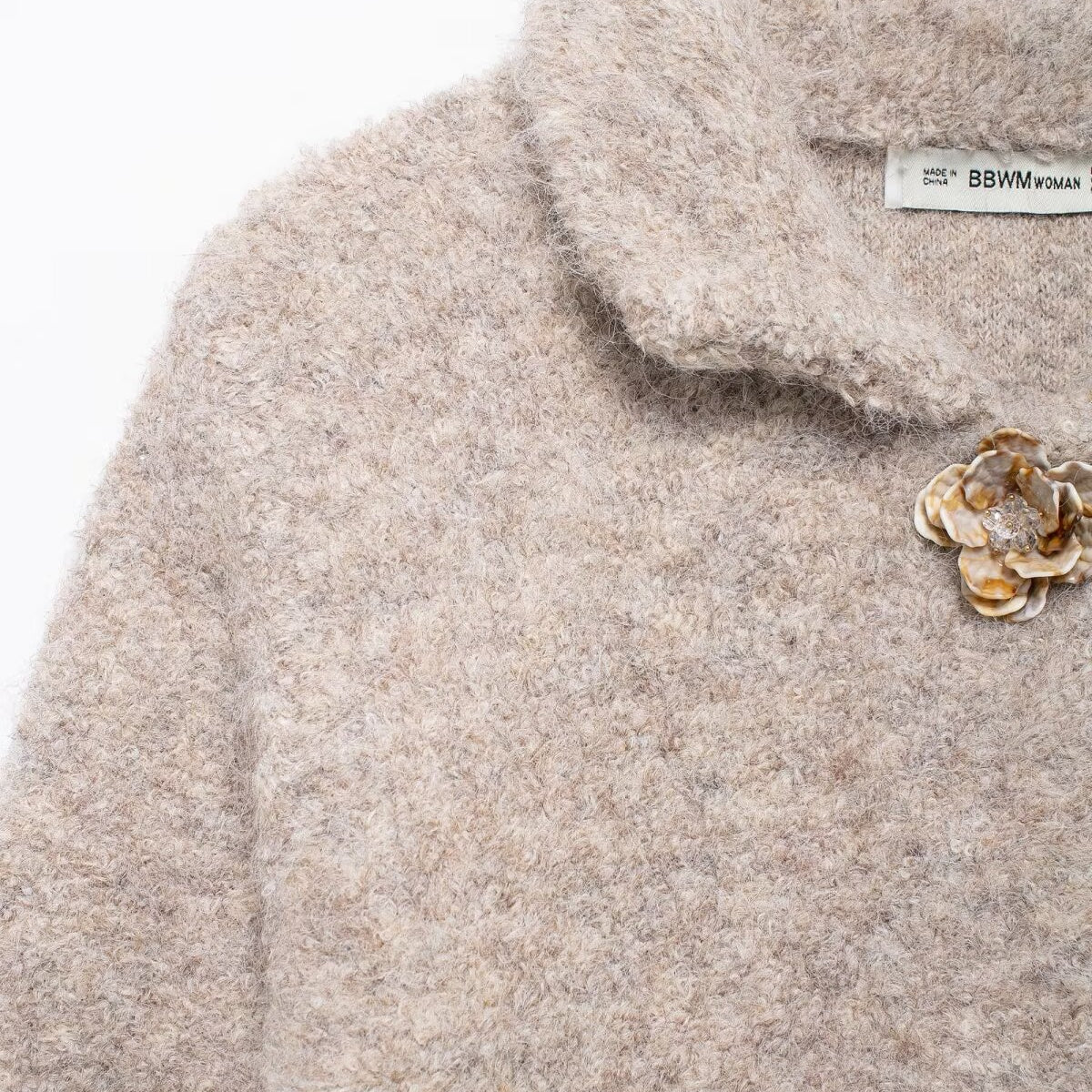 Elegant knitted cardigan with beige fluffy sweater, floral brooches, and Langry fashion label