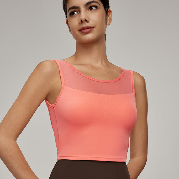 Fashionable coral-colored women’s sleeveless crop top with sheer mesh panel for workout