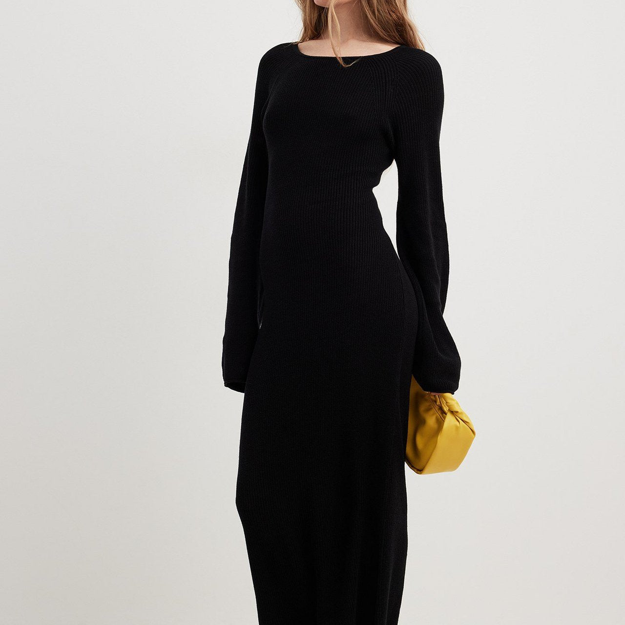 Long black knit dress with balloon sleeves paired with a stylish yellow handbag accessory