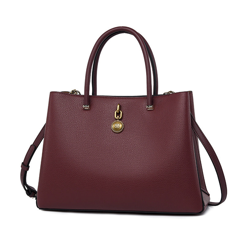 Burgundy leather handbag with gold hardware and dual handles for elegant fashion ملابس