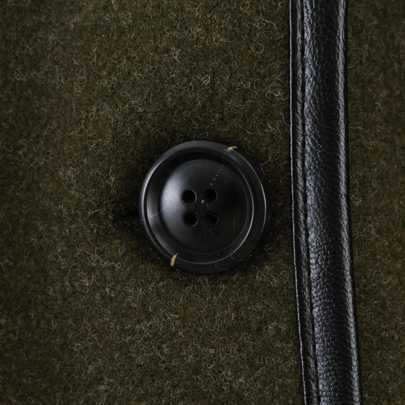 Black button with four holes on textured fabric, Langry fashion coat detail