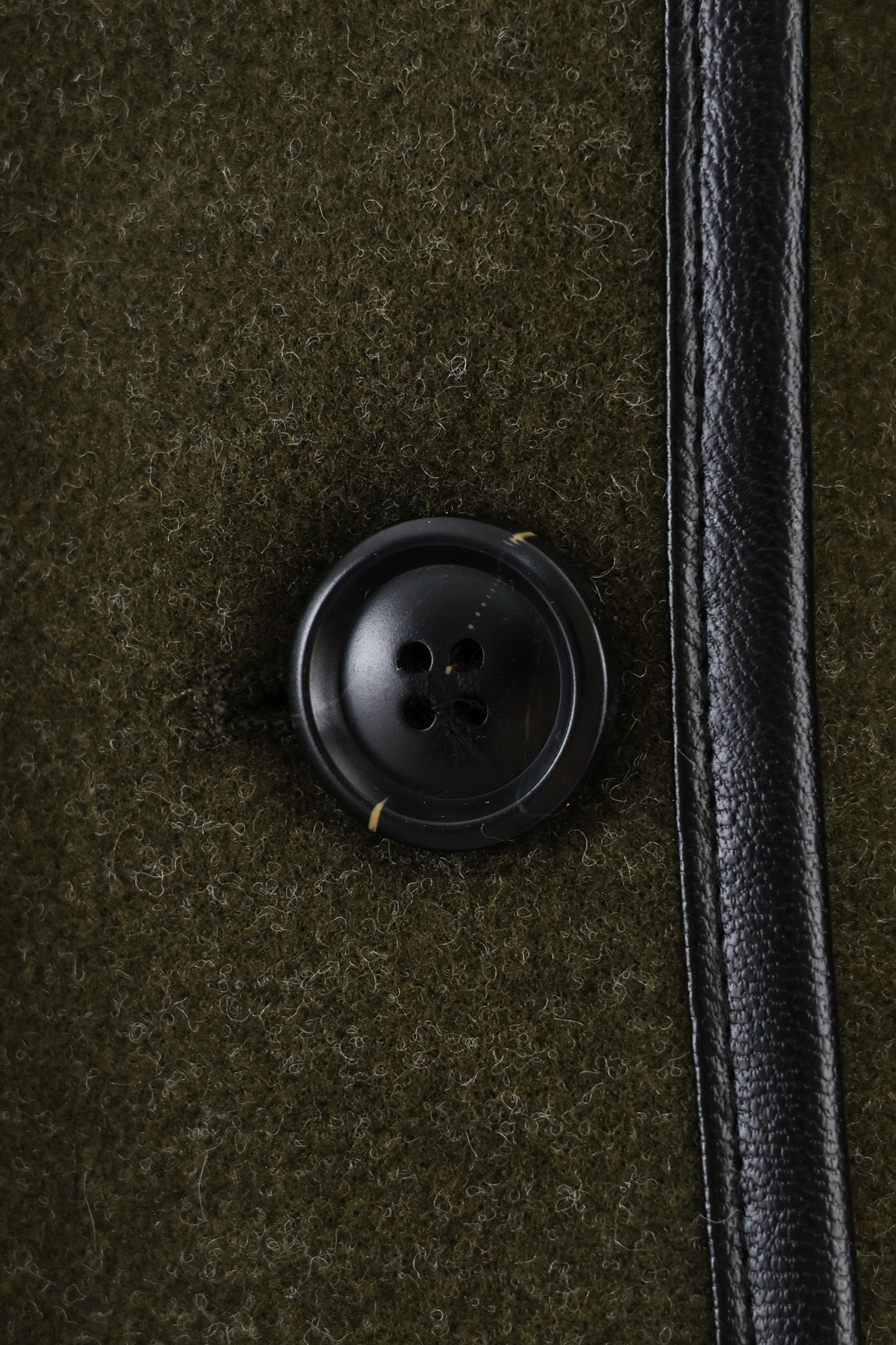 Black button with four holes on textured fabric, Langry fashion coat detail