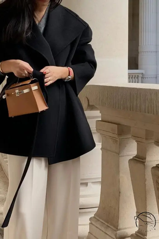 Brown leather Hermes Kelly bag with gold hardware on elegant woolen coat