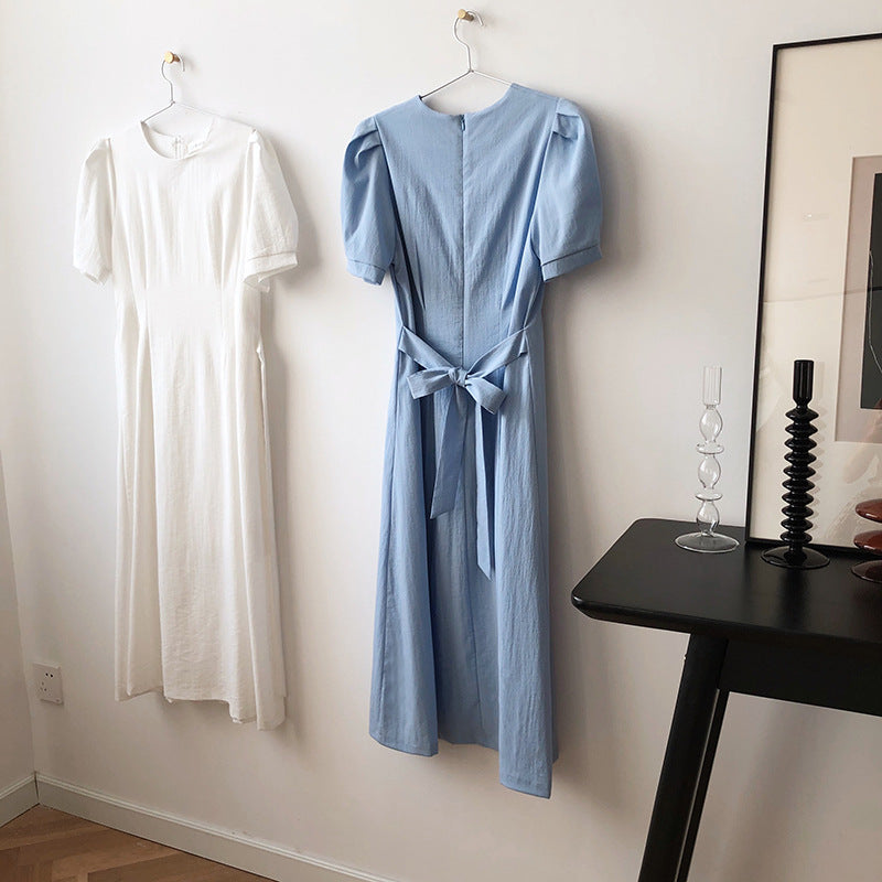 Two elegant puff sleeve dresses hanging on a wall showcasing French Elegant Puff Sleeve Dress style