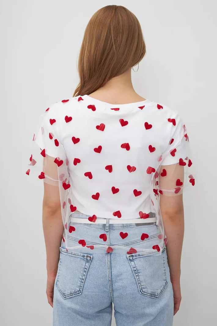 White t-shirt with red heart pattern paired with light blue jeans for elegant fashion ملابس