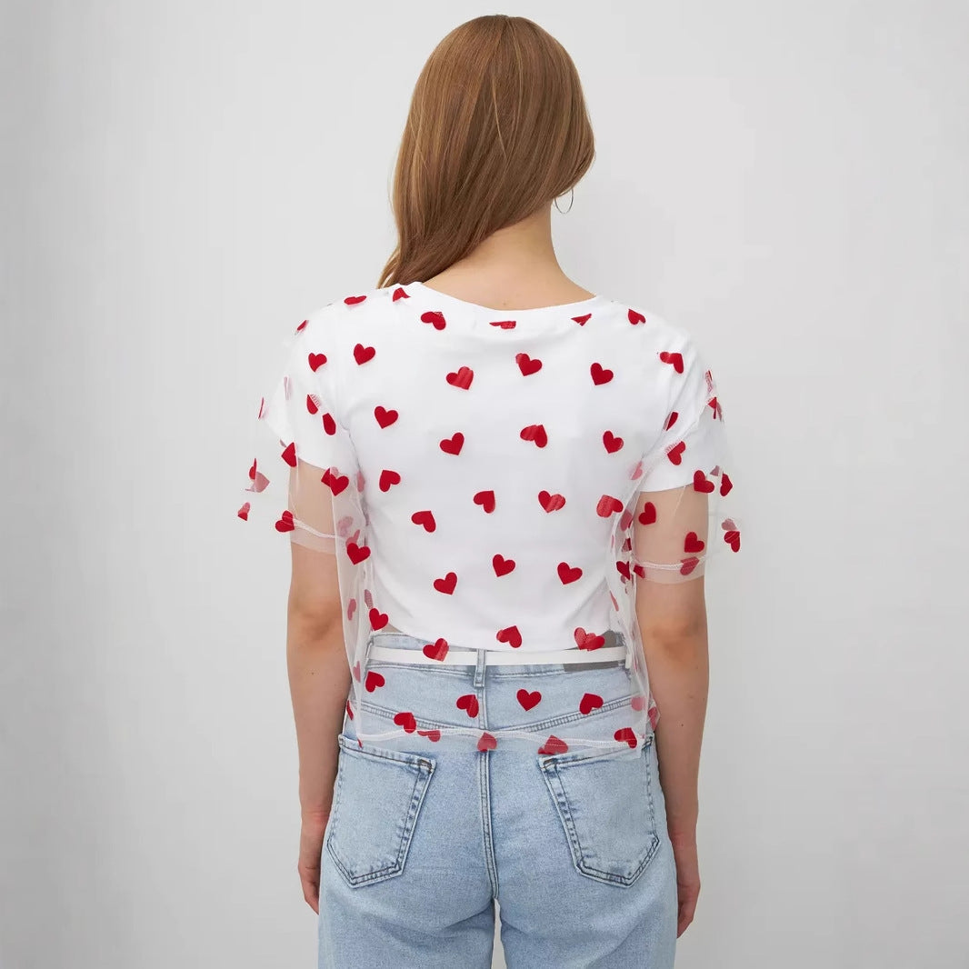 White t-shirt with red heart pattern paired with light blue jeans for elegant fashion ملابس