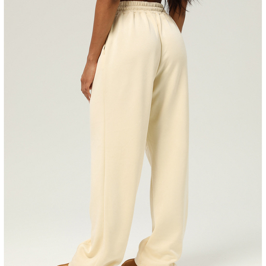 Cream-colored wide-leg sweatpants paired with brown slippers for stylish casual fitness wear