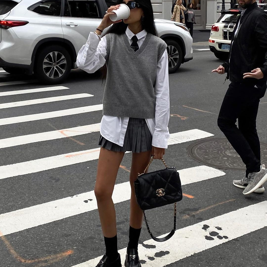 Preppy street style fashion featuring a Loose Knit Vest Sweater, pleated skirt, and boots