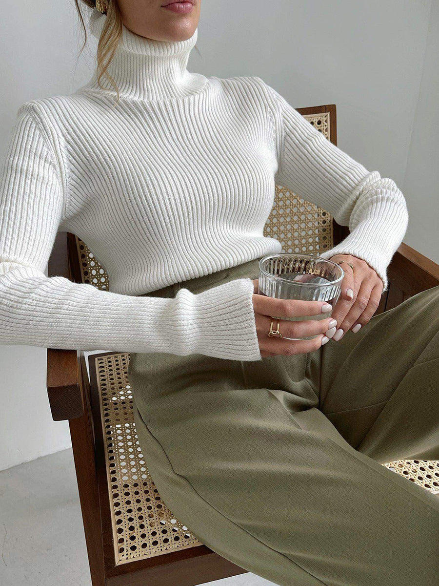 Langry fashion white ribbed turtleneck sweater with olive green pants on perforated chair
