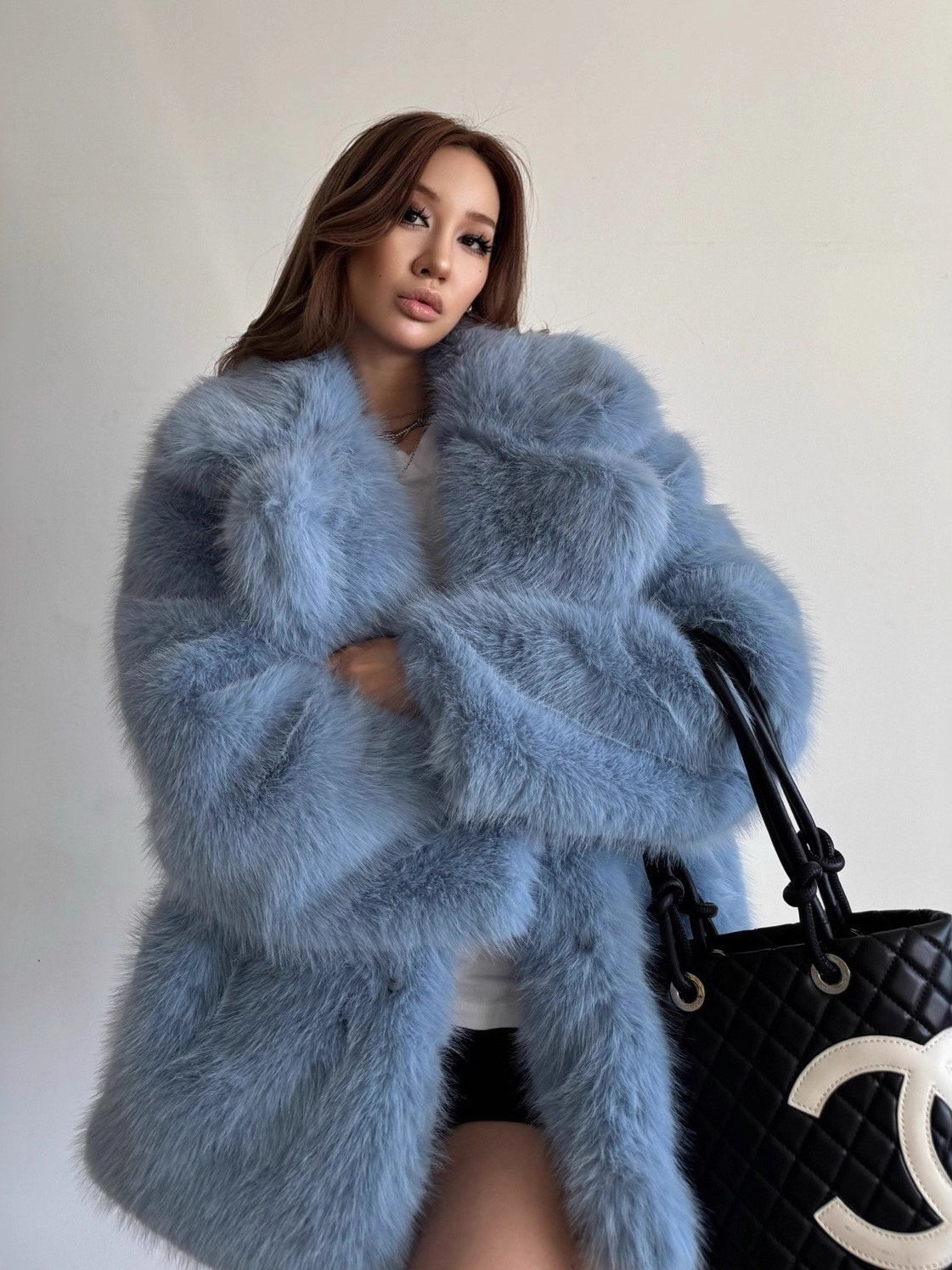 Light blue fluffy faux fur coat with Chanel logo on black tote bag