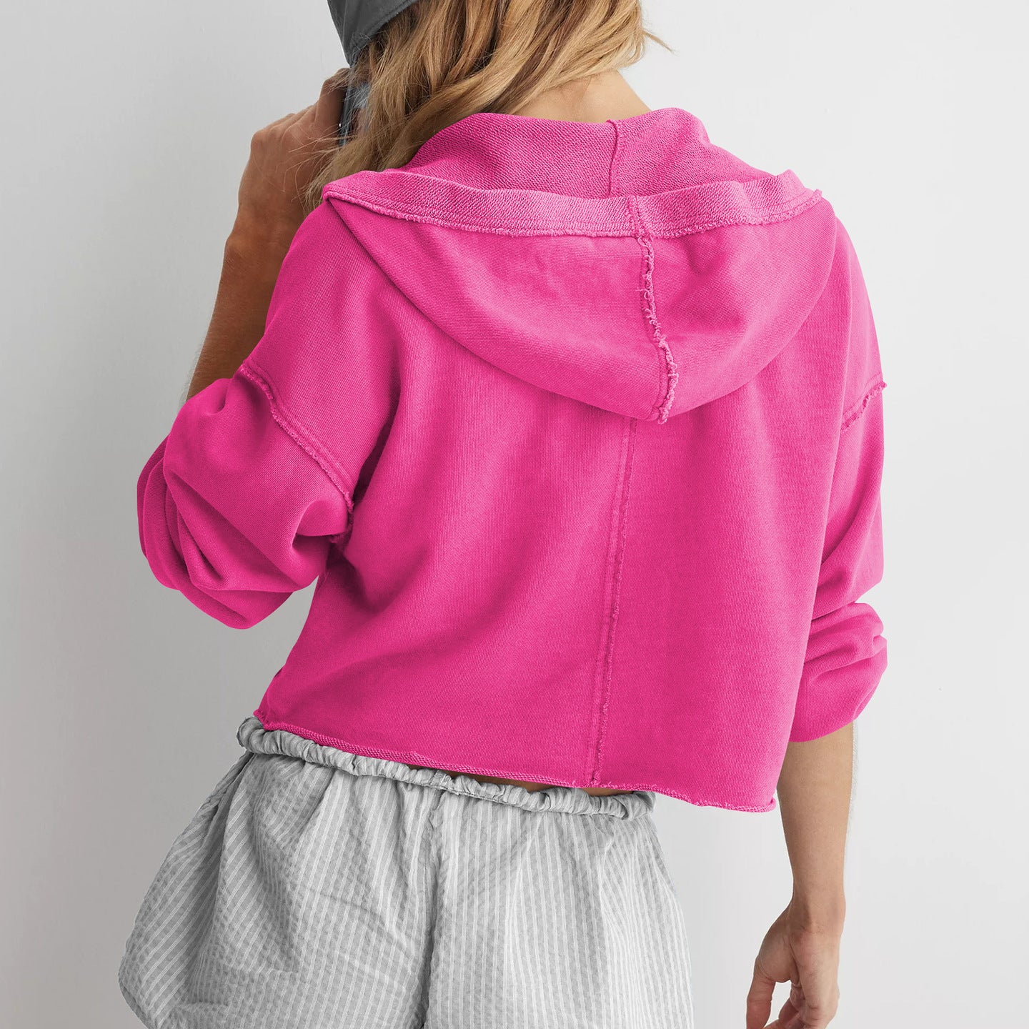 Hot pink cropped hoodie styled with gray striped shorts and a baseball cap, langry fashion