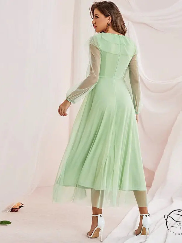 Woman in gorgeous high waist voile A-line dress with mint green midi, sheer long sleeves, layered tulle skirt