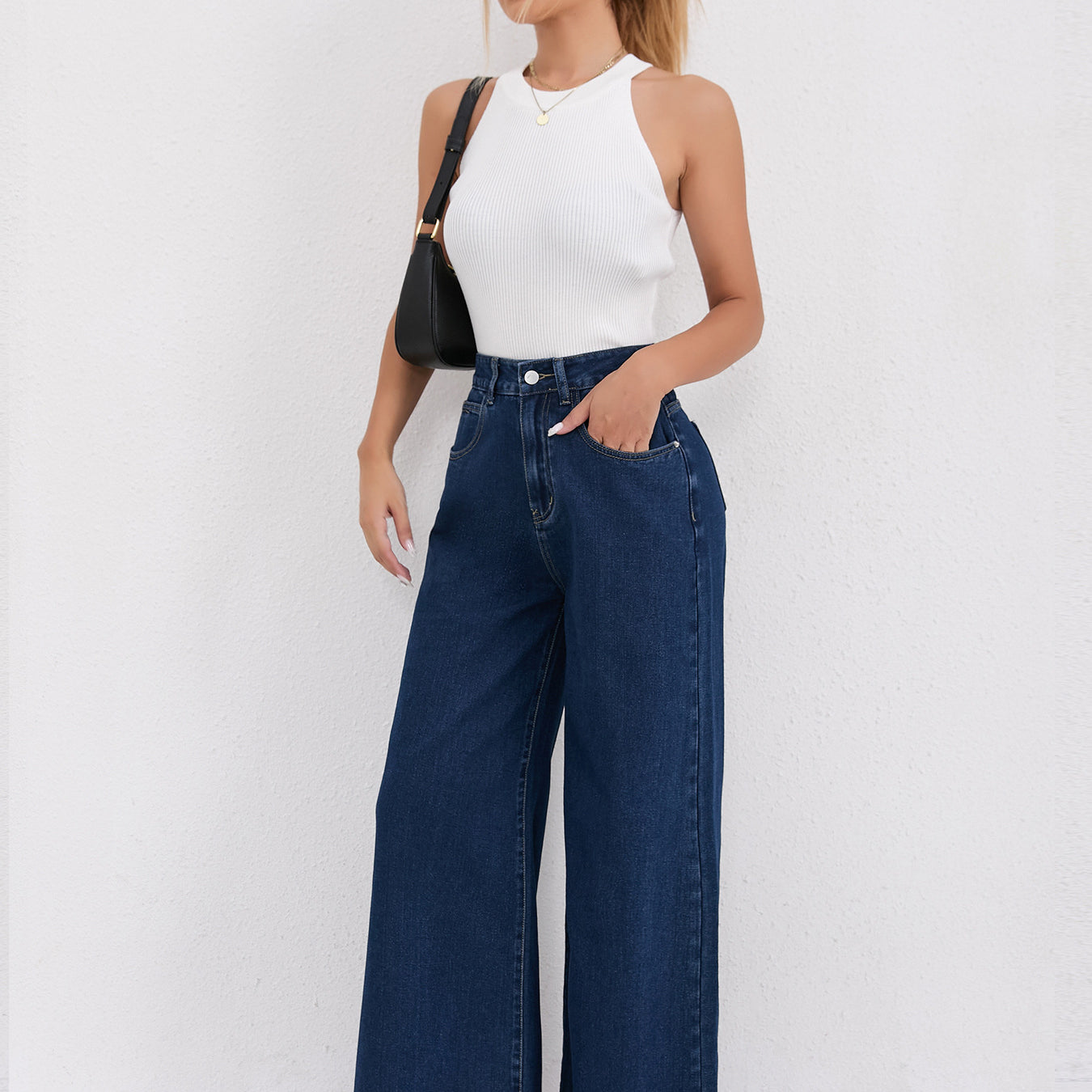 Wide leg dark blue denim jeans paired with a white halter top for chic fashion