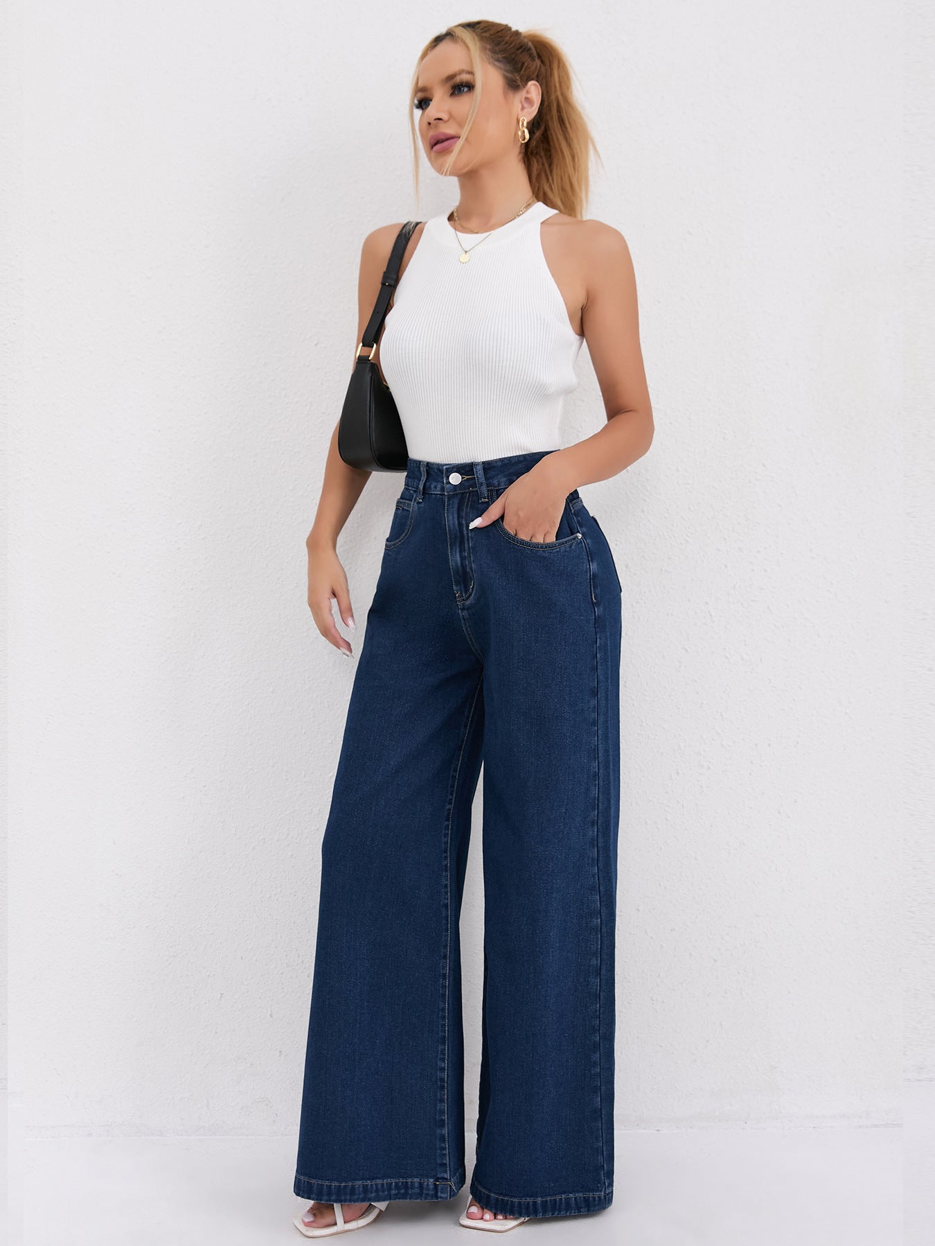 Wide leg dark blue denim jeans paired with a white halter top for chic fashion
