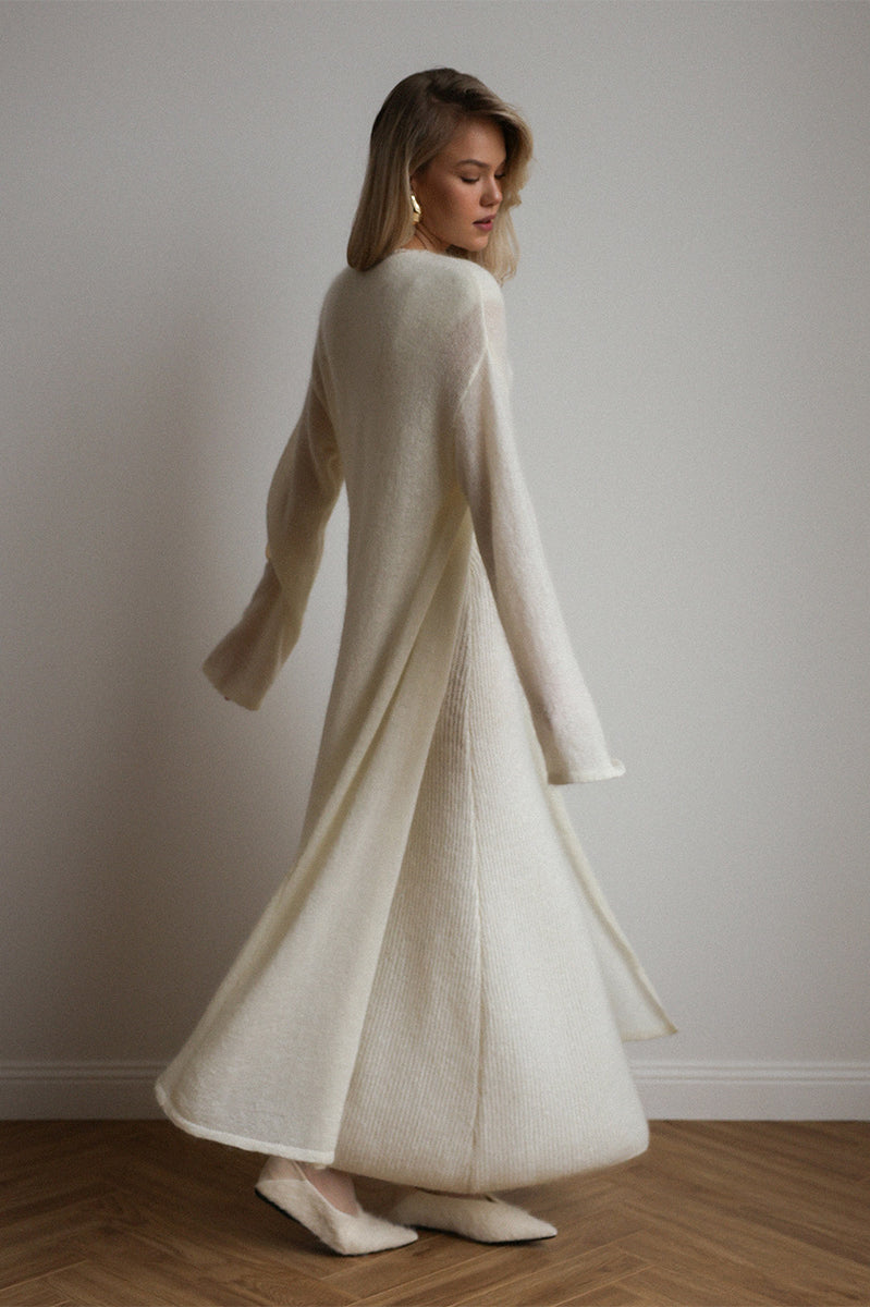 Cream-colored knitted cardigan with fur trim over sleeveless dress