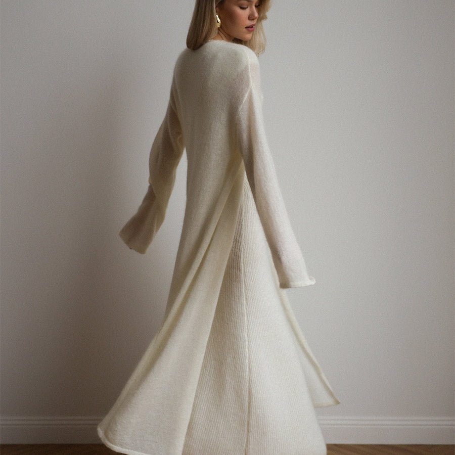 Cream-colored knitted cardigan with fur trim over sleeveless dress