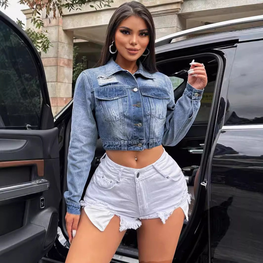 Woman wearing a loose short denim coat in light blue distressed denim and white frayed shorts