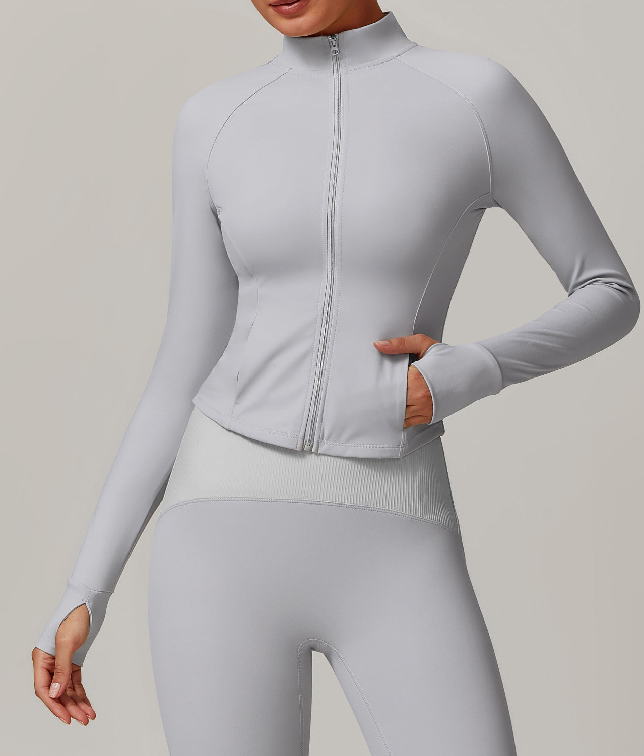 Light gray zip-up athletic jacket with mock neck and thumb holes for stylish yoga fashion