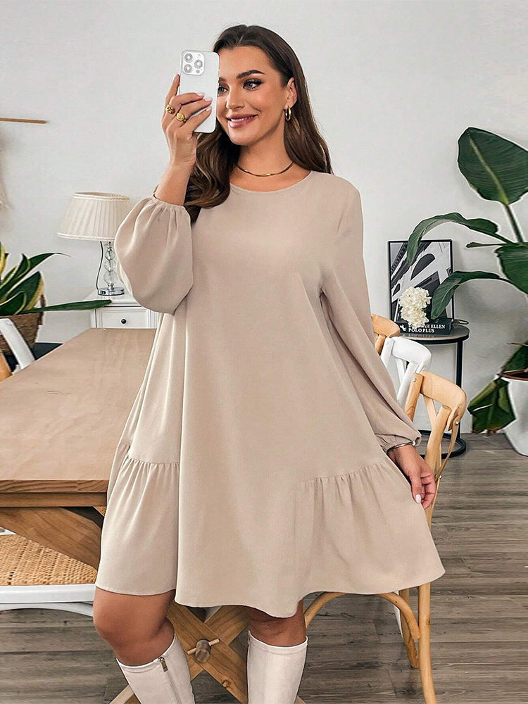 Woman in beige long-sleeved midi dress and white knee-high boots showcasing fashionable winter style