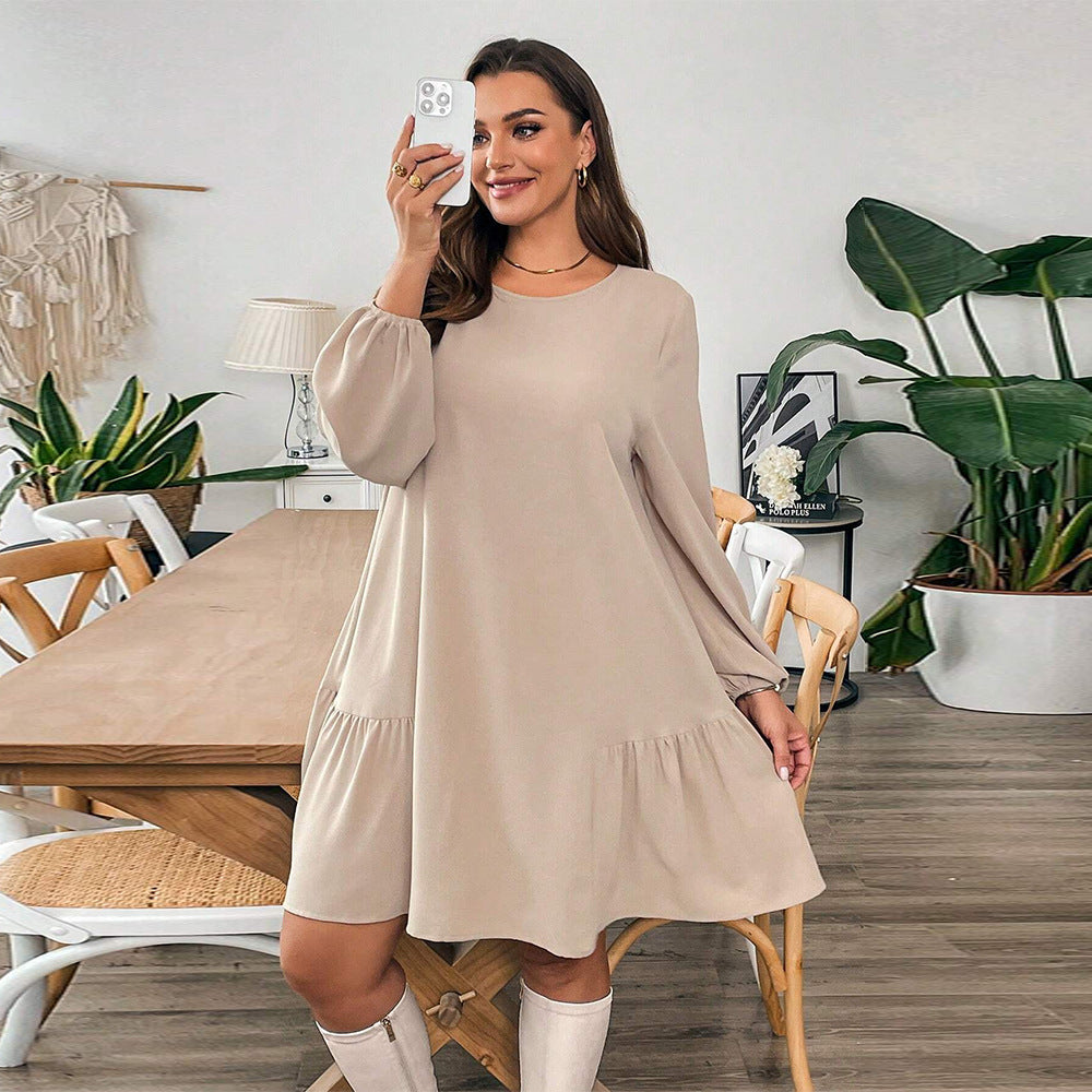 Woman in beige long-sleeved midi dress and white knee-high boots showcasing fashionable winter style
