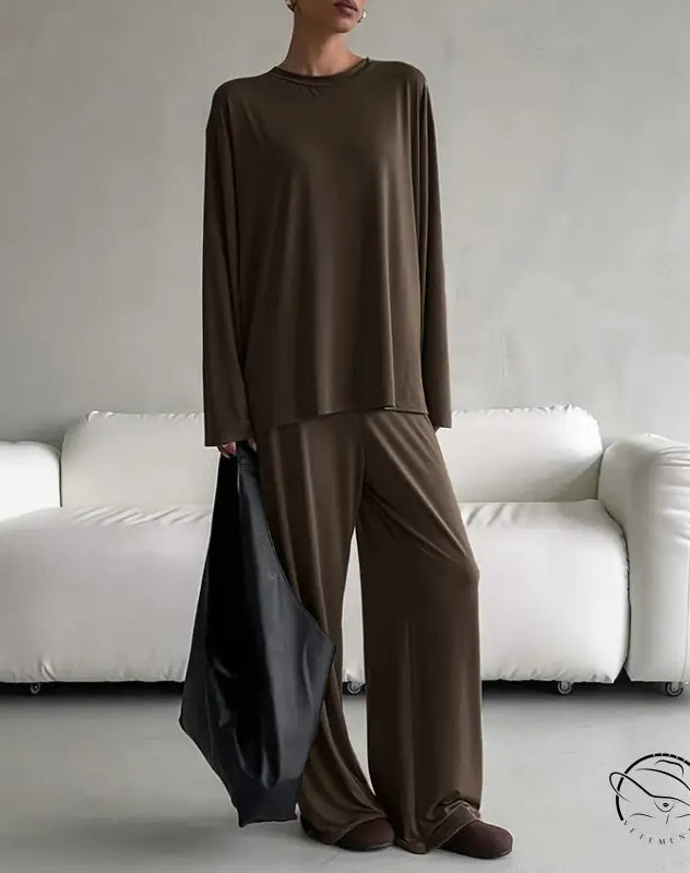 Woman in round neck loose long-sleeve brown pajama suit with wide-leg pants and tote bag