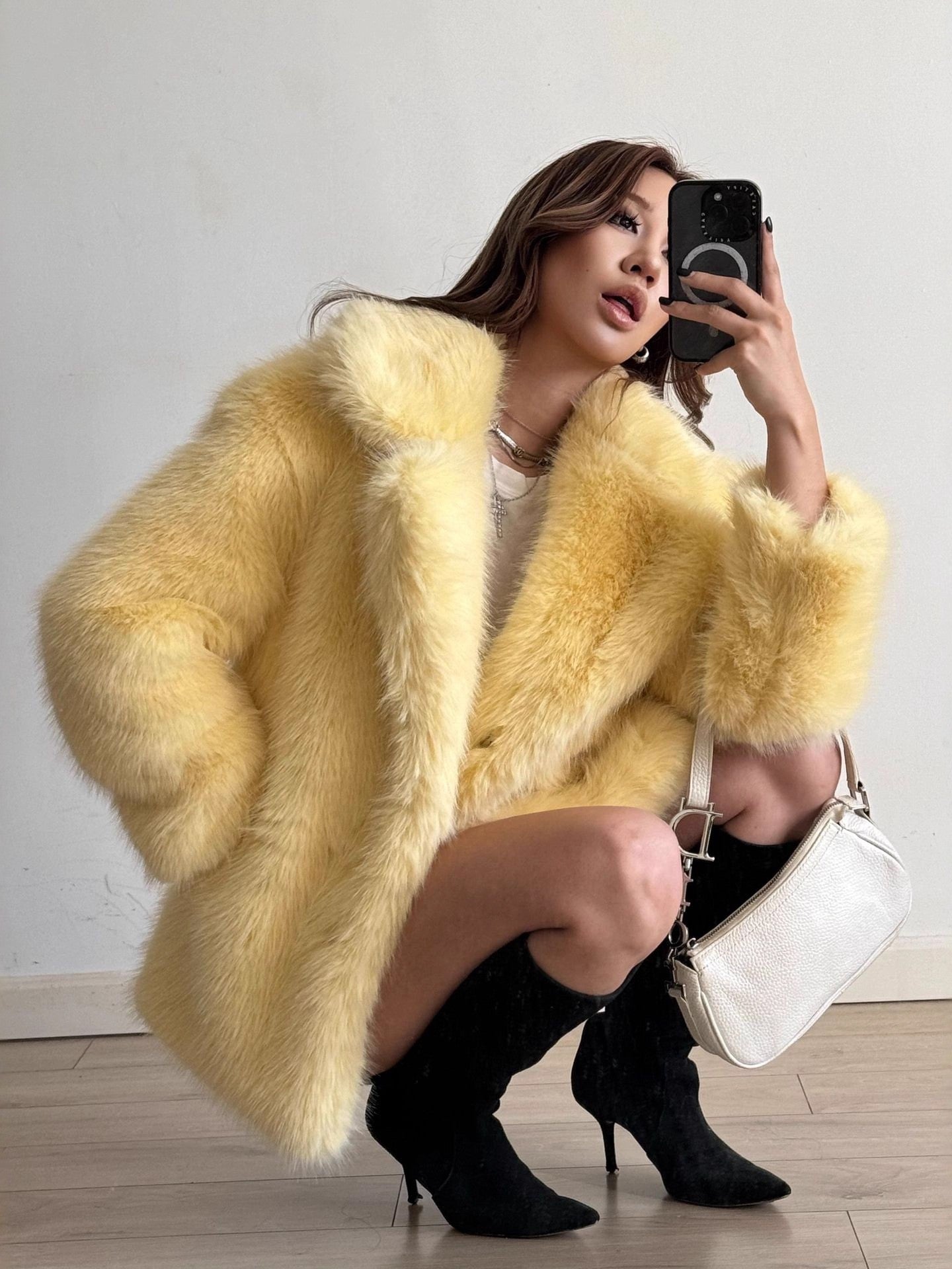Yellow fluffy faux fur coat with black boots and white handbag