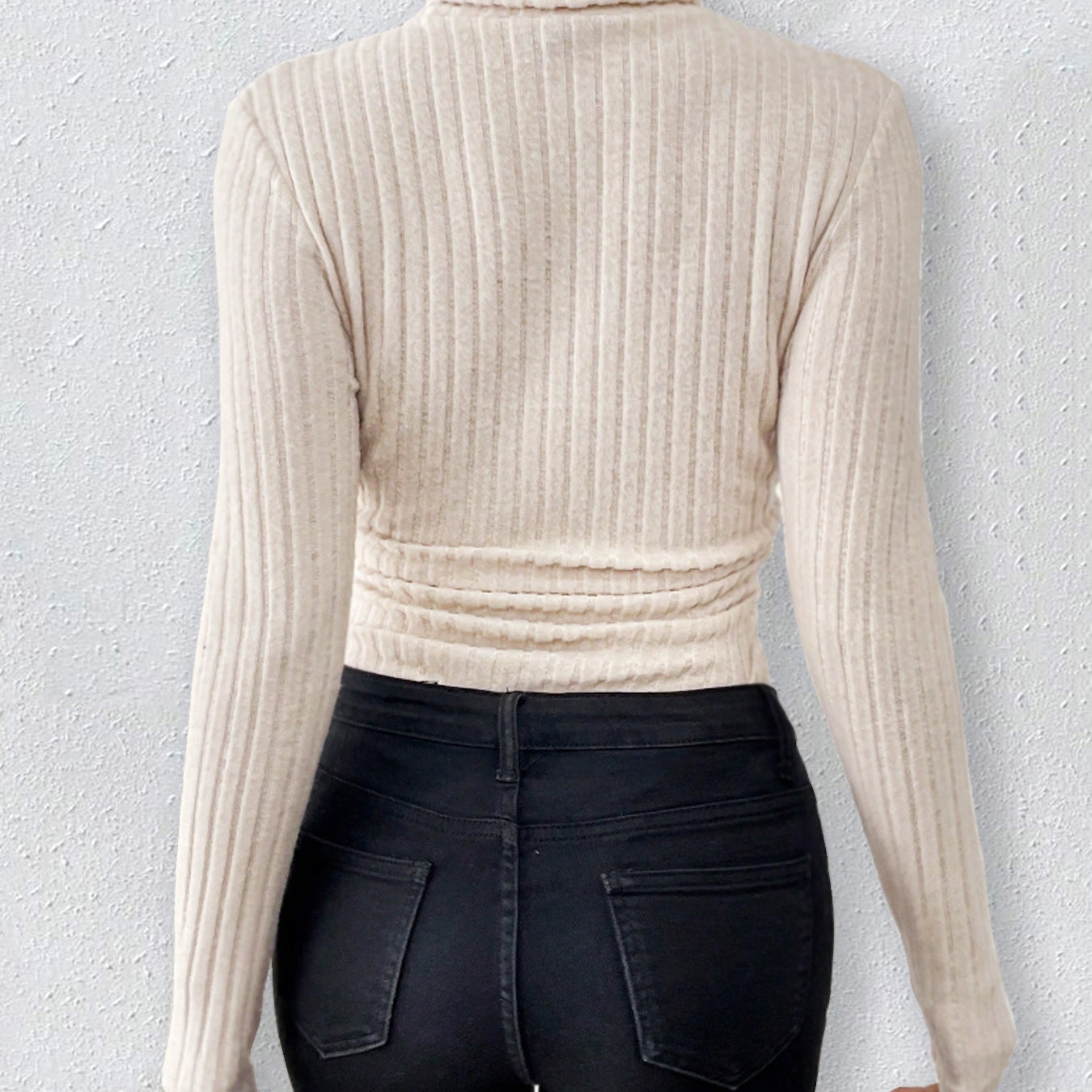 Cream-colored ribbed turtleneck sweater styled with dark jeans for elegant fashion versatility