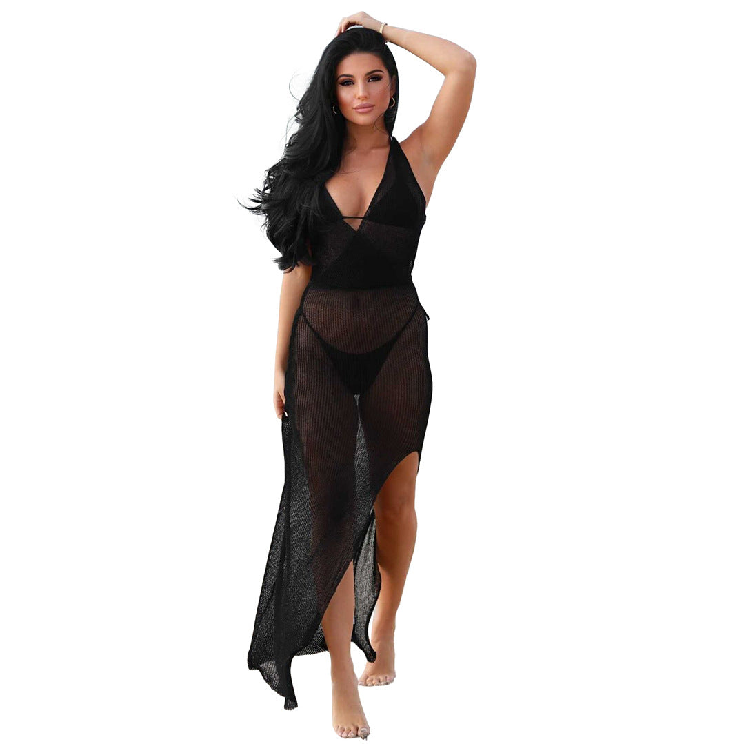Woman in black swimsuit and sheer cover-up wearing knitted beach maxi dress on light camel beach