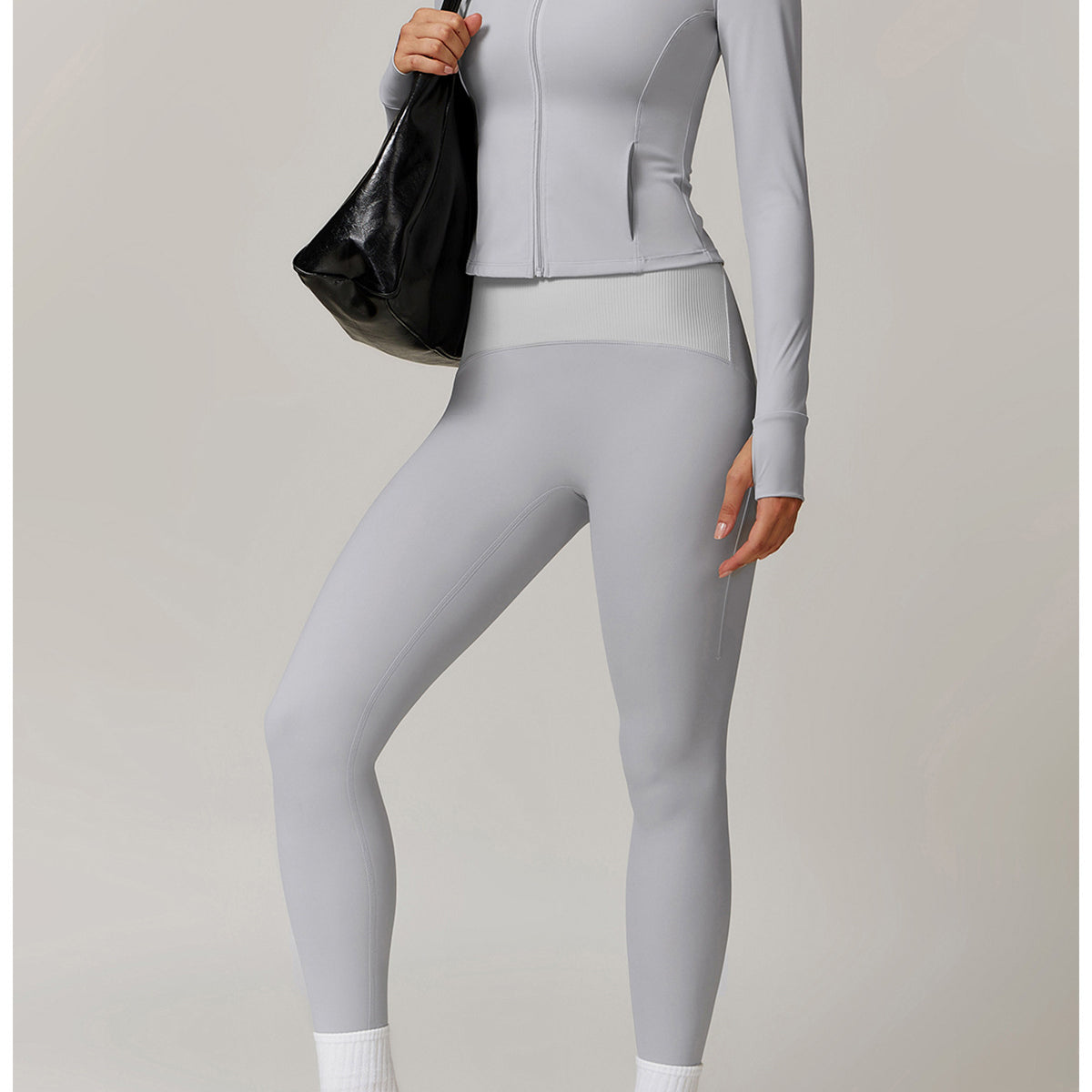 Light grey athletic two-piece set featuring a zip-up jacket and leggings, paired with sneakers