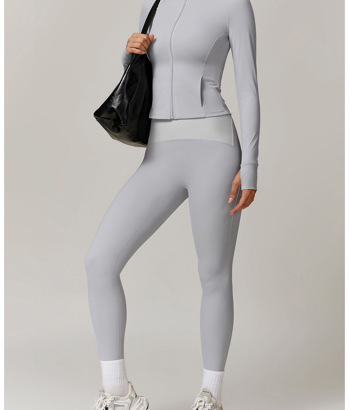 Light grey athletic two-piece set featuring a zip-up jacket and leggings, paired with sneakers
