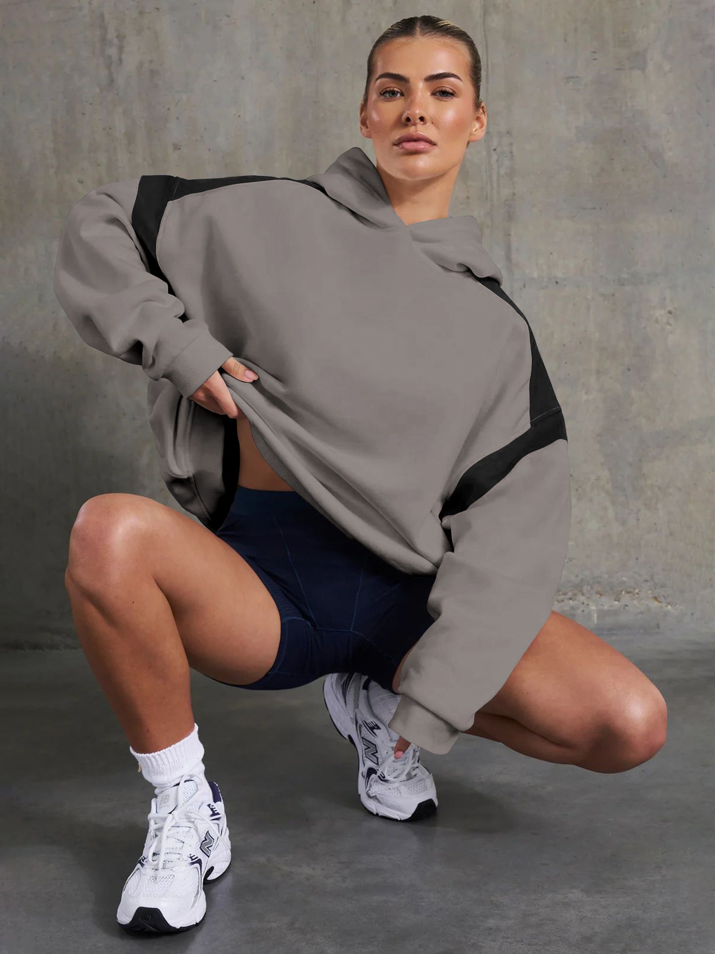 Woman in gray and black hoodie showcasing langry fashion style with navy shorts and white sneakers