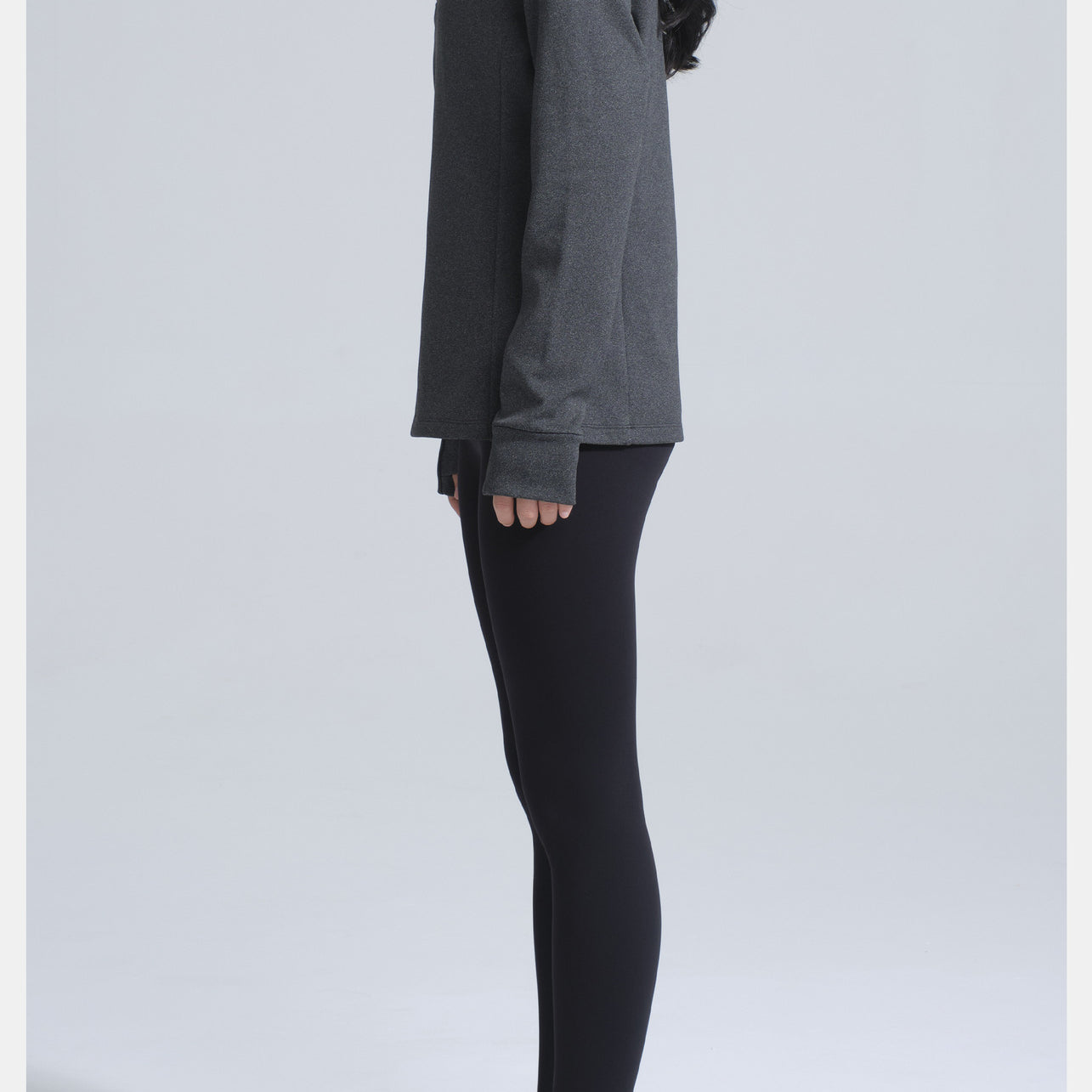 Person wearing dark gray long-sleeved yoga jacket, black leggings, and athletic shoes for winter thermal fashion