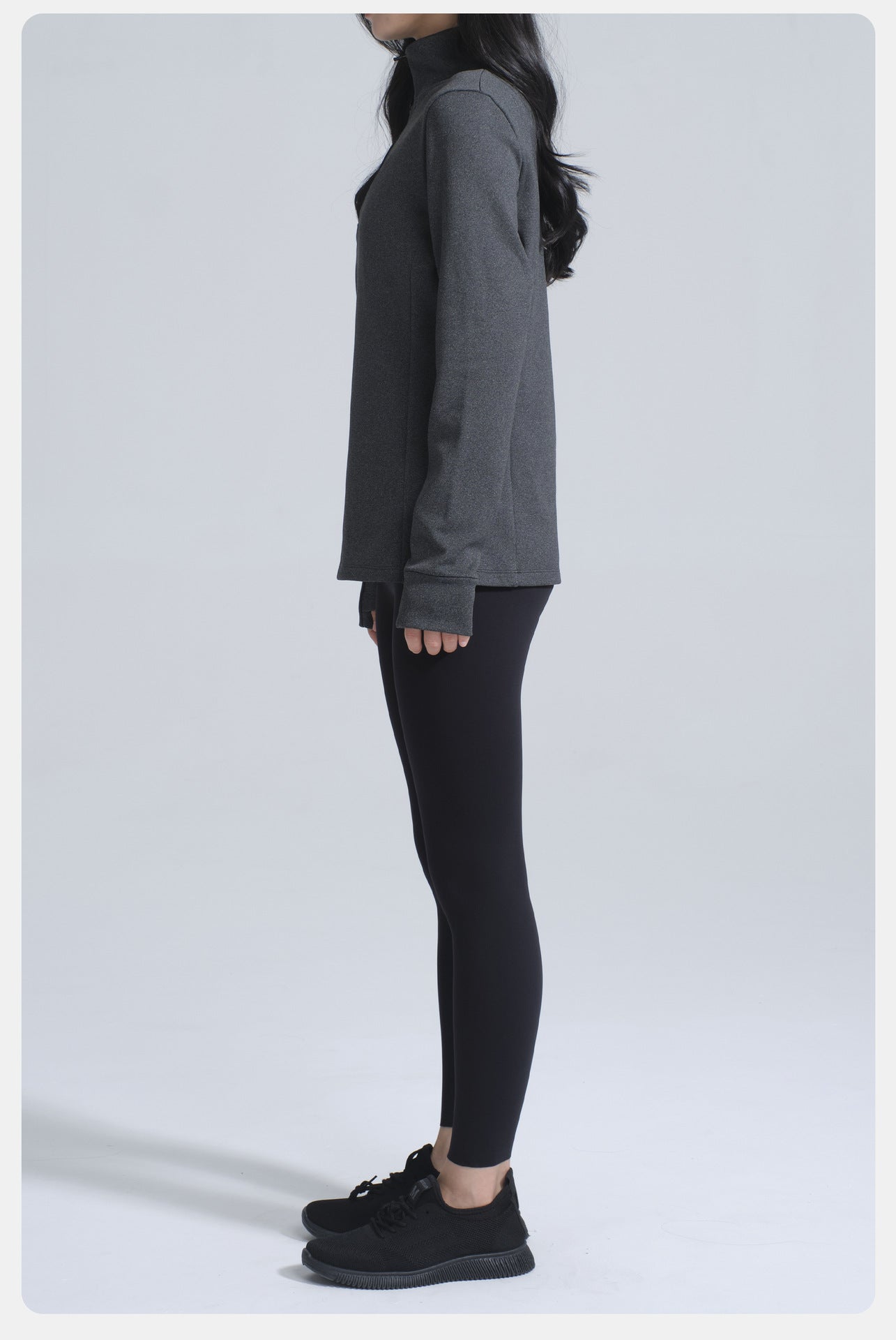 Person wearing dark gray long-sleeved yoga jacket, black leggings, and athletic shoes for winter thermal fashion