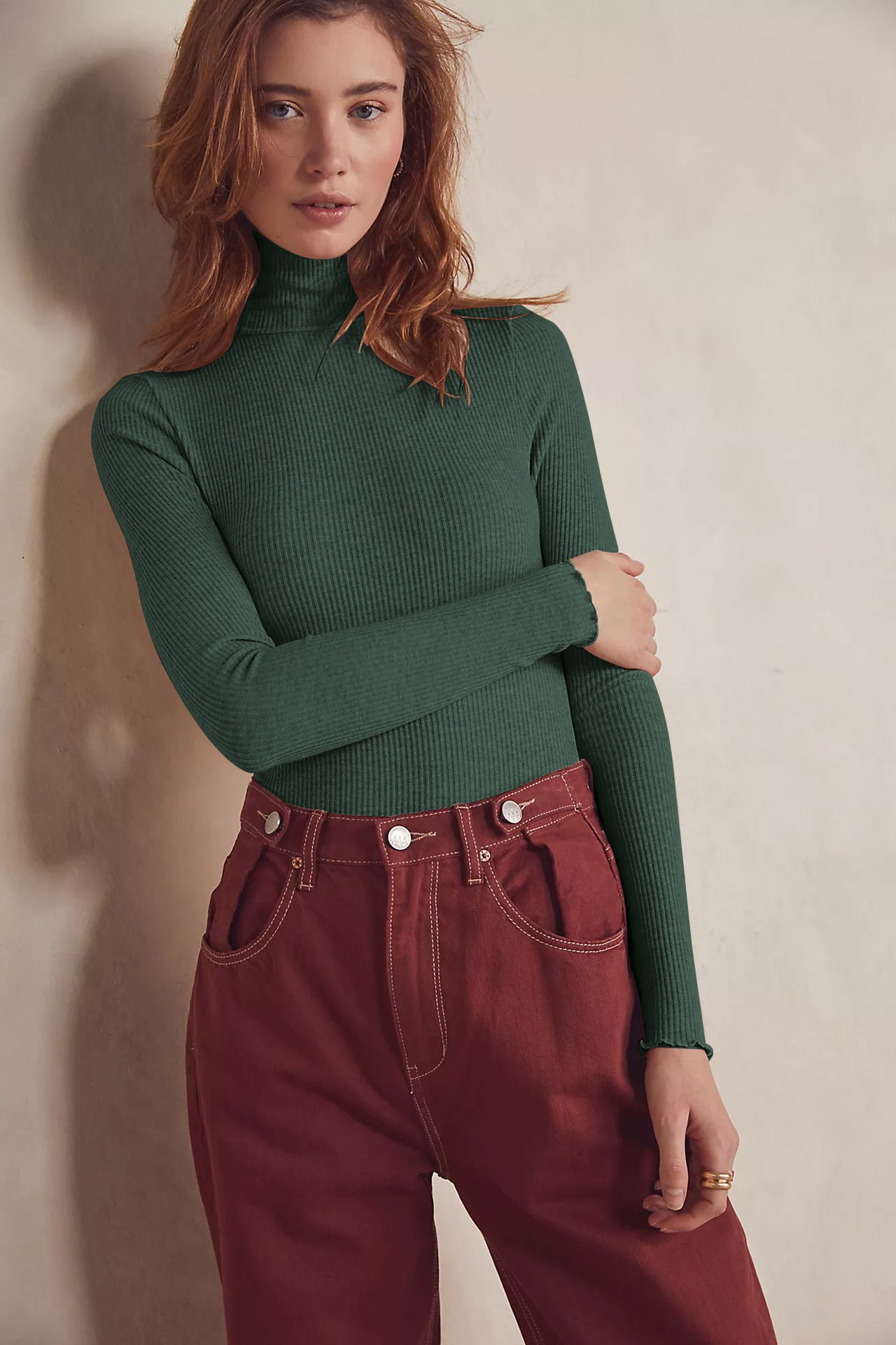 Woman in green turtleneck and red pants wearing high collar long sleeve slim rib bodysuit