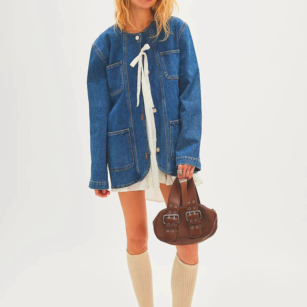 Fashionable cowboy coat styled with a denim jacket, white dress, knee-high socks, and loafers
