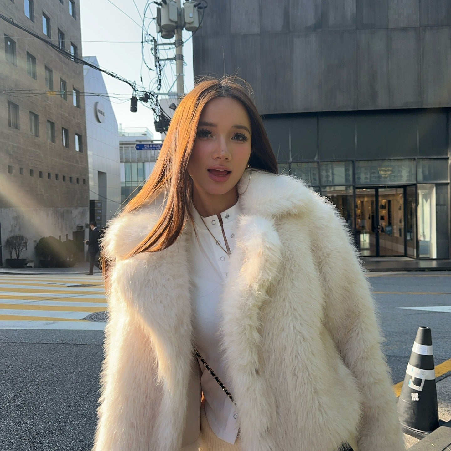 Short loose casual faux fur coat with white trim and Chanel bag