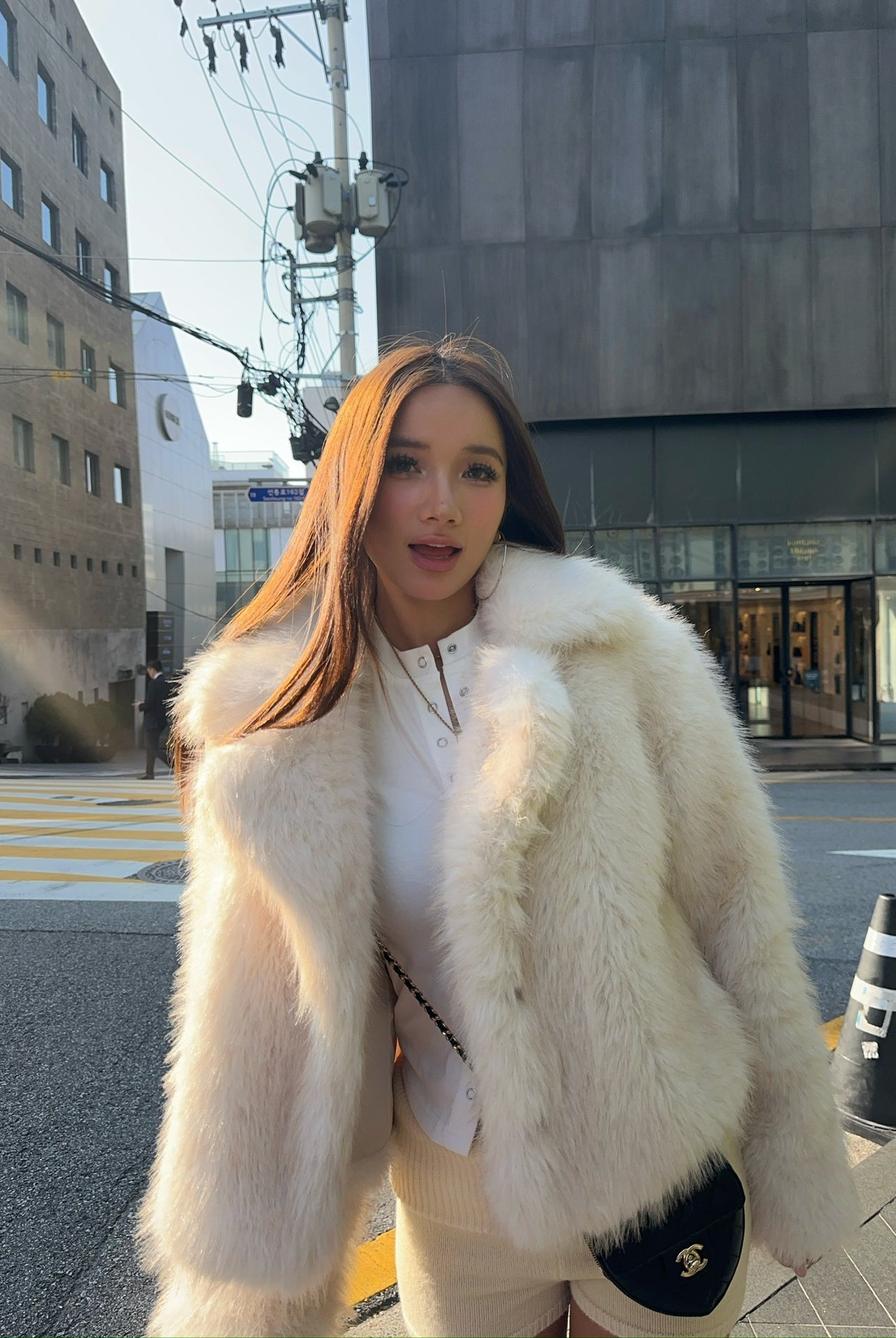 Short loose casual faux fur coat with white trim and Chanel bag