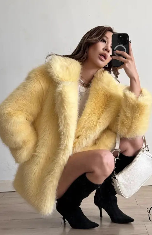 Yellow faux fur coat with black heels and white handbag