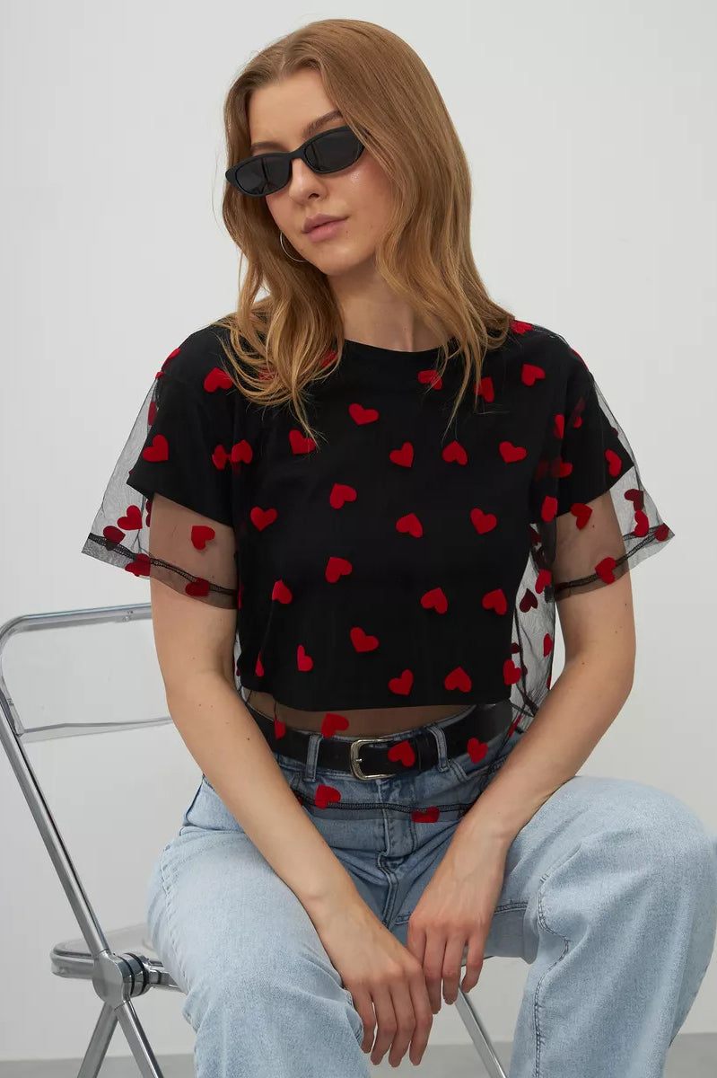 Black mesh top with red heart patterns paired with light blue jeans for trendy fashion ملابس