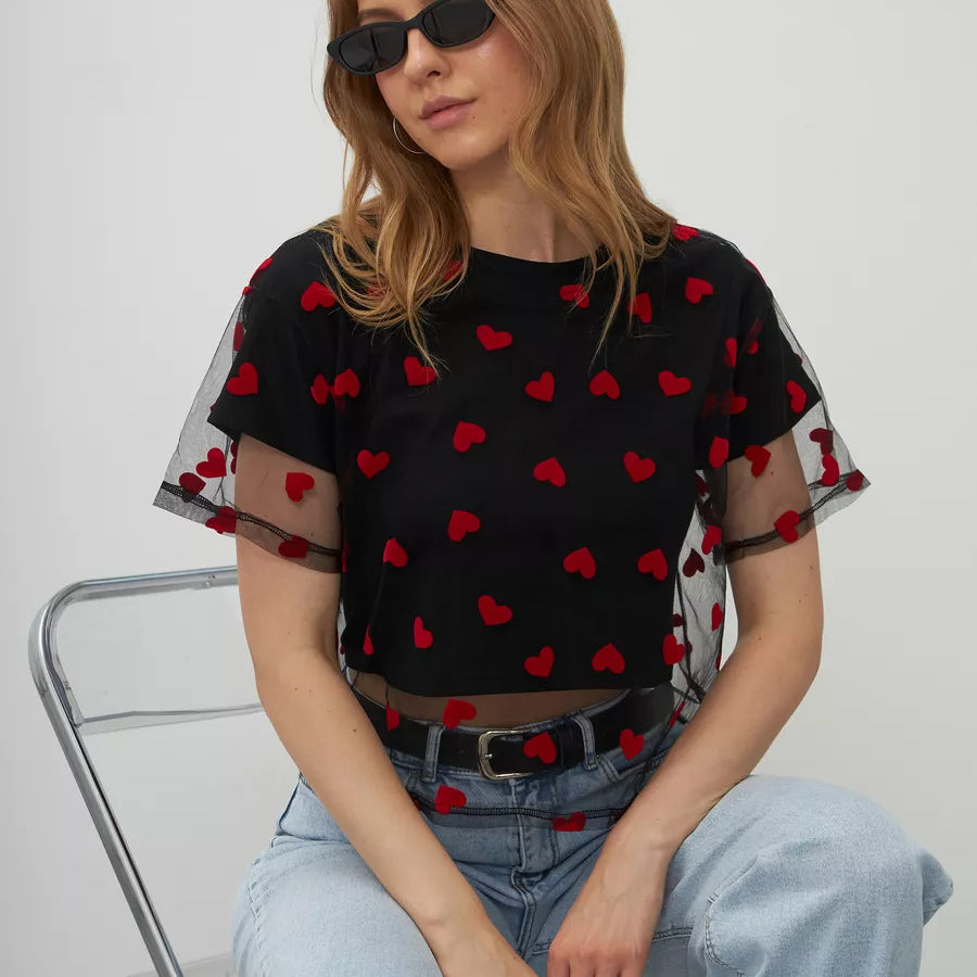 Black mesh top with red heart patterns paired with light blue jeans for trendy fashion ملابس