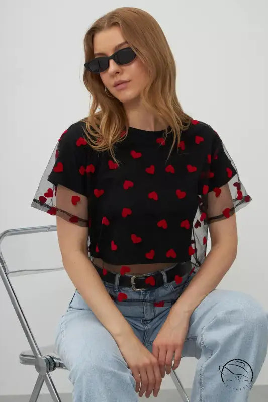Elegant faux cotton short top in black mesh with red hearts and sheer sleeves over light blue jeans